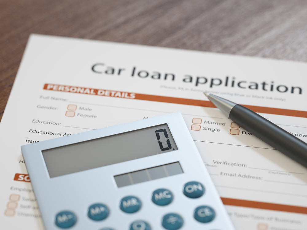 Car loan application form with calculator and pen representing negative equity auto financing