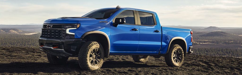 2026 Chevy Silverado 1500 standing on top of cliff surrounded by mountains.