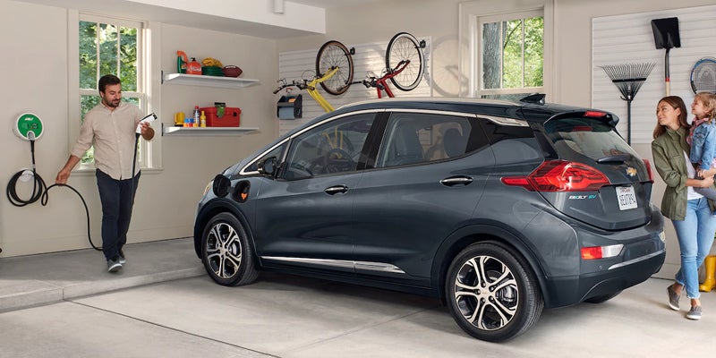 Chevrolet Bolt EV parked in the garage as the owner has the charger in the hand ready to charge his vehicle