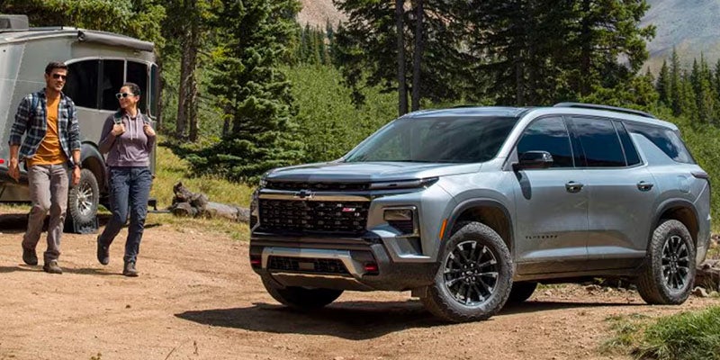 Chevrolet Traverse parked in the forest as two people come over to get more equipment out of the vehicle